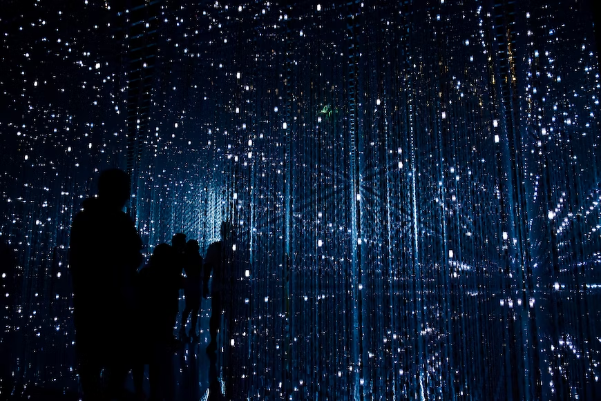 Dark figures of people entering a space bathed in futuristic lights